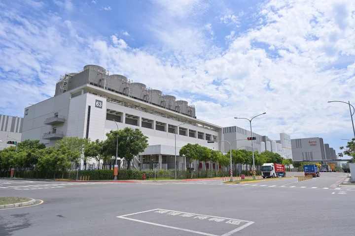 Bâtiments blancs de l'usine Fab 18 de TSMC à Tainan, avec une route et des camions au premier plan