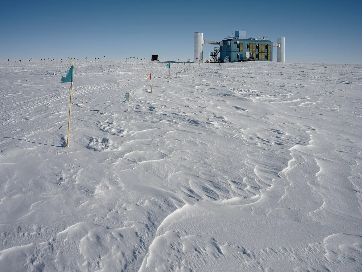 Bâtiment du laboratoire IceCube au milieu d'une étendue de neige au pôle Sud, sous un ciel bleu