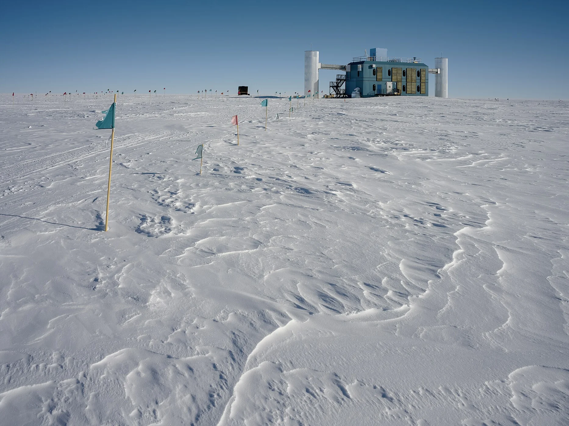 Bâtiment du laboratoire IceCube au milieu d'une étendue de neige au pôle Sud, sous un ciel bleu