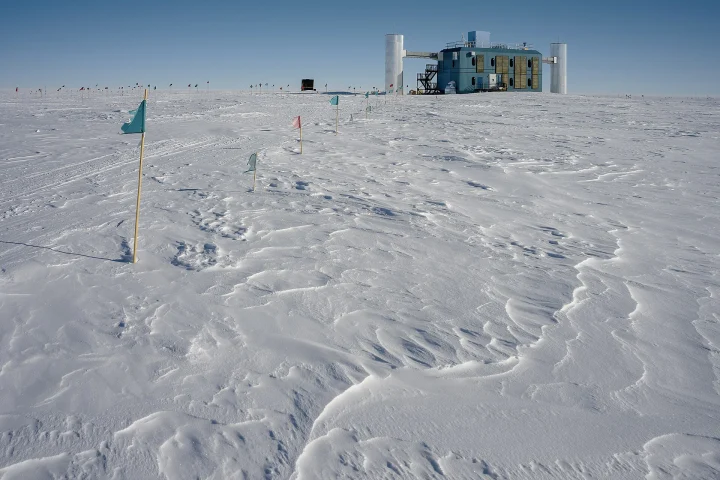 Bâtiment du laboratoire IceCube au milieu d'une étendue de neige au pôle Sud, sous un ciel bleu