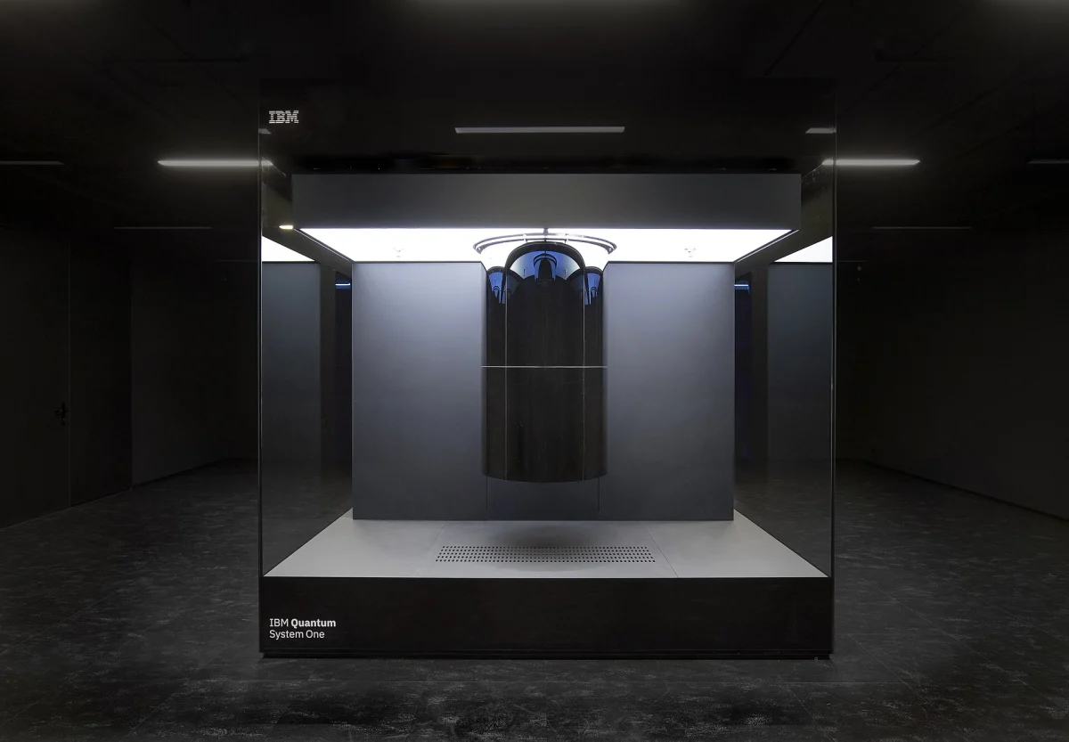 Ordinateur quantique IBM Quantum System One : cryostat cylindrique noir suspendu dans un cube de verre éclairé