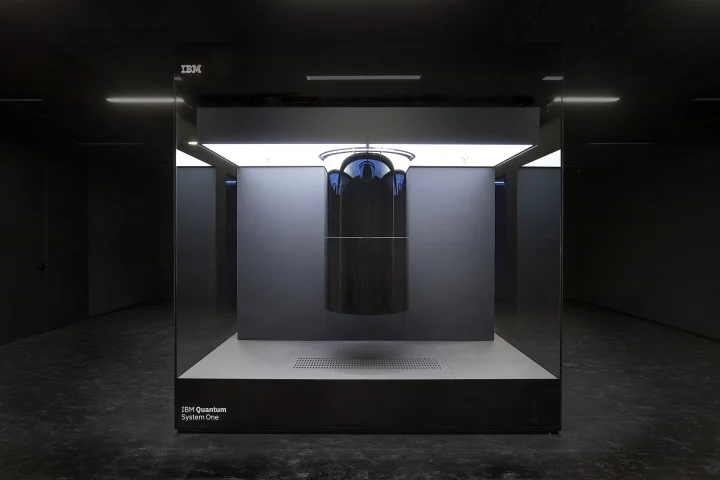 Ordinateur quantique IBM Quantum System One : cryostat cylindrique noir suspendu dans un cube de verre éclairé