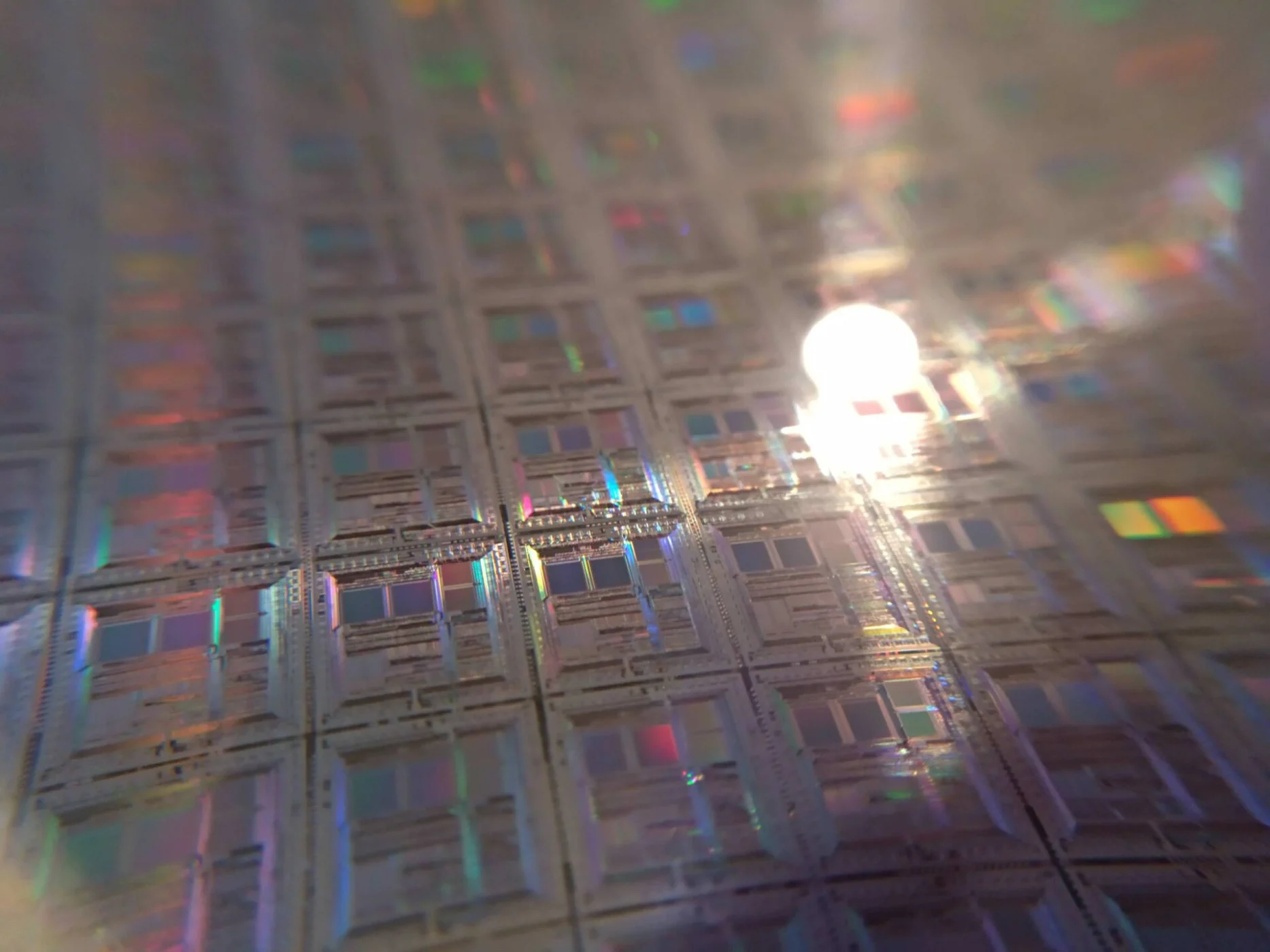 Gros plan sur une plaquette de silicium aux reflets irisés, couverte de puces identiques
