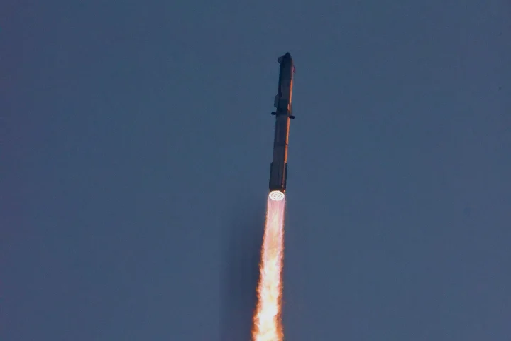 Fusée Starship en ascension dans un ciel bleu, avec une longue flamme orangée