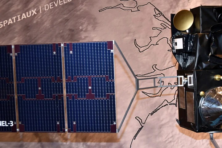 Maquette du satellite Sentinel-3 avec son panneau solaire bleu déployé devant un fond illustré